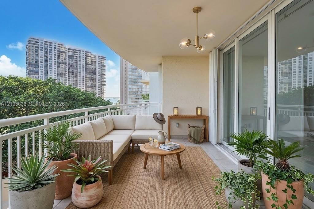 Covered balcony featuring tile flooring, metal railing, and a multi-light brass chandelier