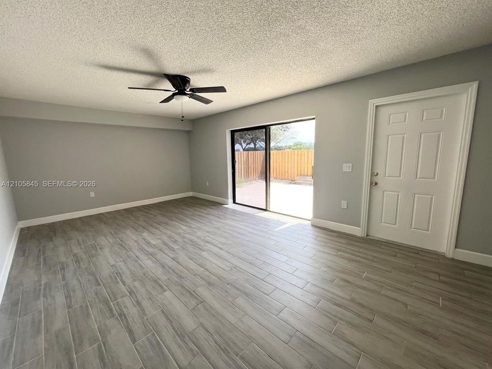 Wood-finish tile flooring, sliding glass door, ceiling fan, and six-panel door
