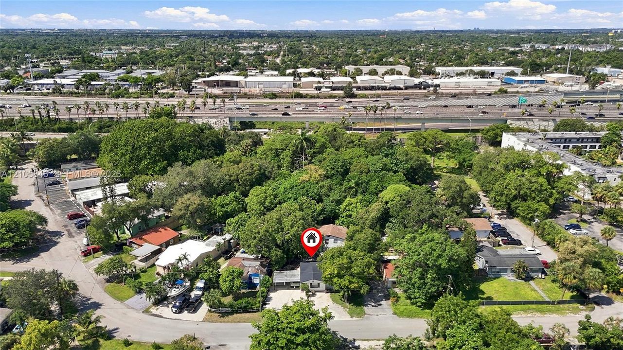 Aerial perspective featuring a single-story residence situated on a lot with mature tree canopy and paved driveway