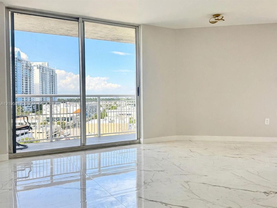 Large-format polished tile flooring, floor-to-ceiling sliding glass doors, and a private balcony with metal railing
