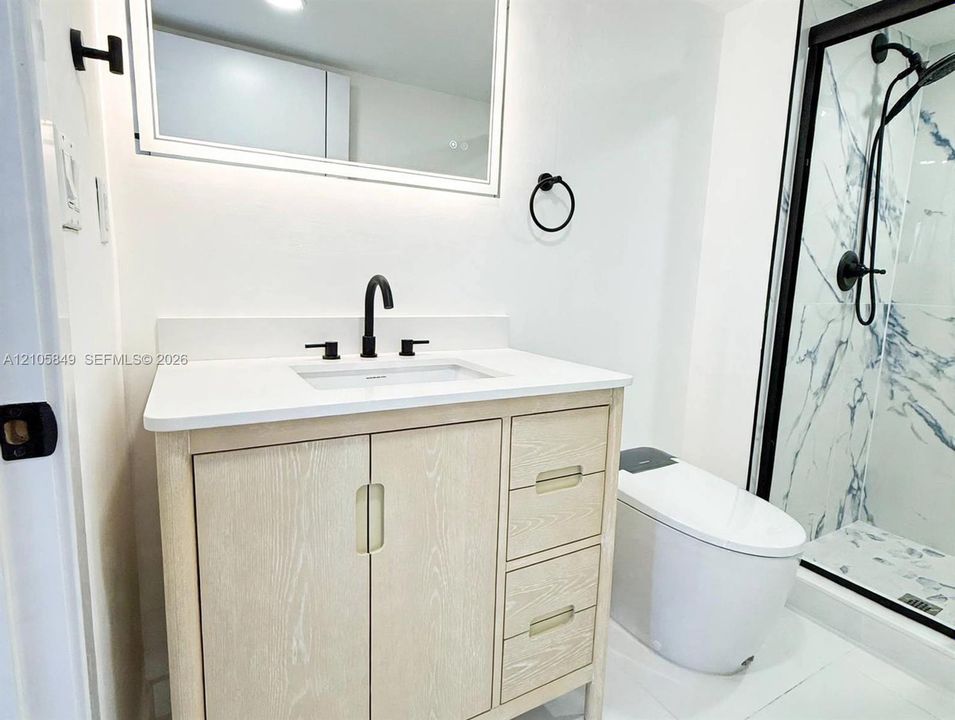 Light wood-finish vanity with a white countertop, undermount sink, matte black faucet, and walk-in shower featuring patterned tile surrounds and a matte black rainfall showerhead