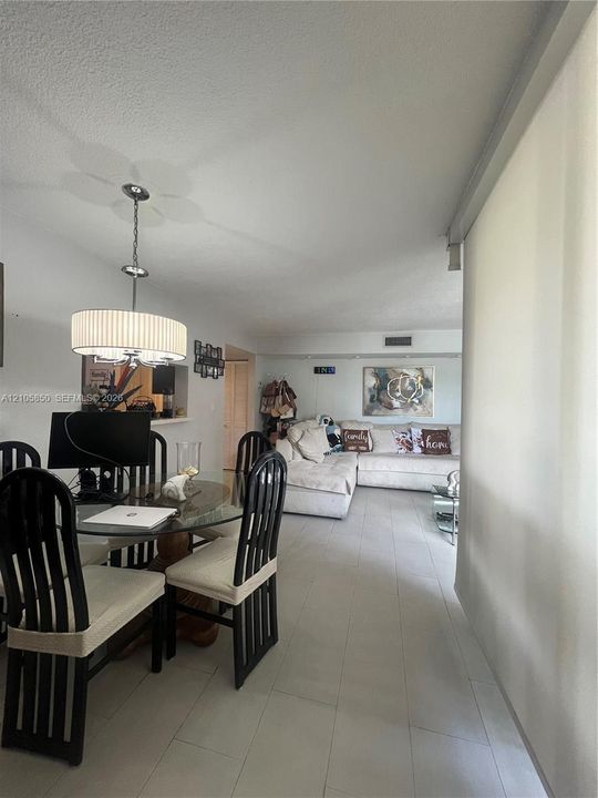 Neutral-toned ceramic tile flooring, drum-style pendant lighting with a metallic finish, and a pass-through opening