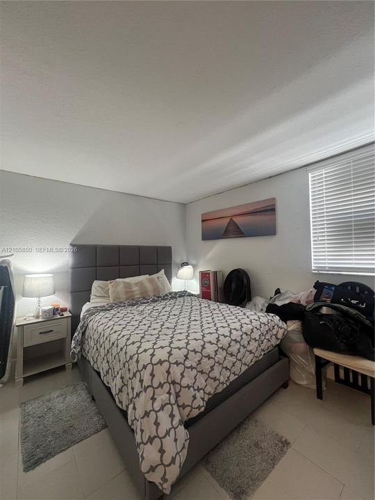 Room featuring neutral-toned walls, tile flooring, and a window with horizontal blinds