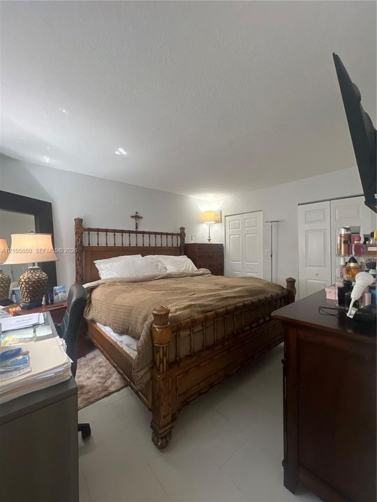 Room featuring neutral-toned walls, smooth-finish ceiling, large-format tile flooring, and dual bi-fold closet doors