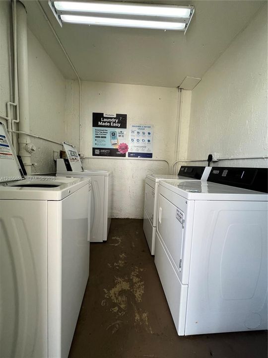 Laundry facility featuring multiple washer and dryer units and overhead fluorescent lighting