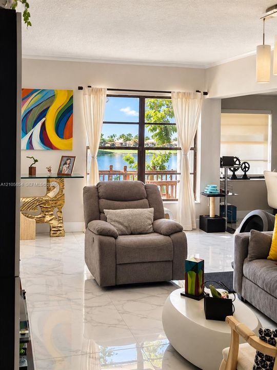 Large picture window featuring water scenery, polished stone-finish tile flooring, and a multi-pendant ceiling light fixture