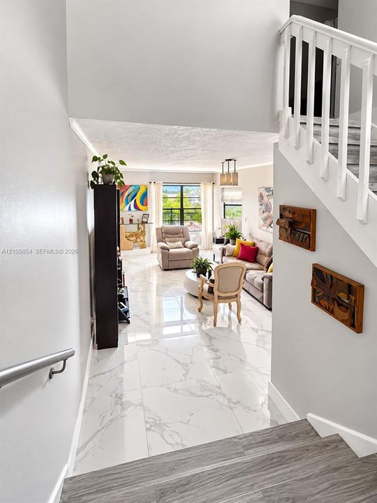 Large-format tile flooring with polished finish, staircase with wood-finish treads and white balusters, metal handrail. Beautiful lake views welcome you the moment you enter the home.