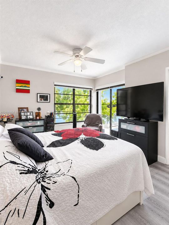 Spacious master bedroom featuring breathtaking lake views through an expansive window and sliding glass door, filling the room with natural light and creating a serene retreat.