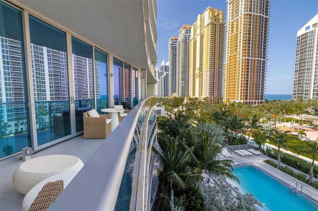 Curved balcony featuring glass panel railings, expansive floor-to-ceiling windows, and tile flooring