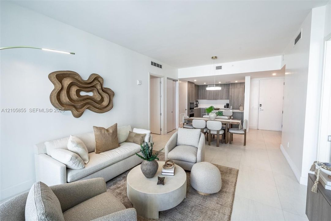 Open-concept floor plan featuring large-format tile flooring, recessed lighting, and kitchen cabinetry with a wood-grain finish
