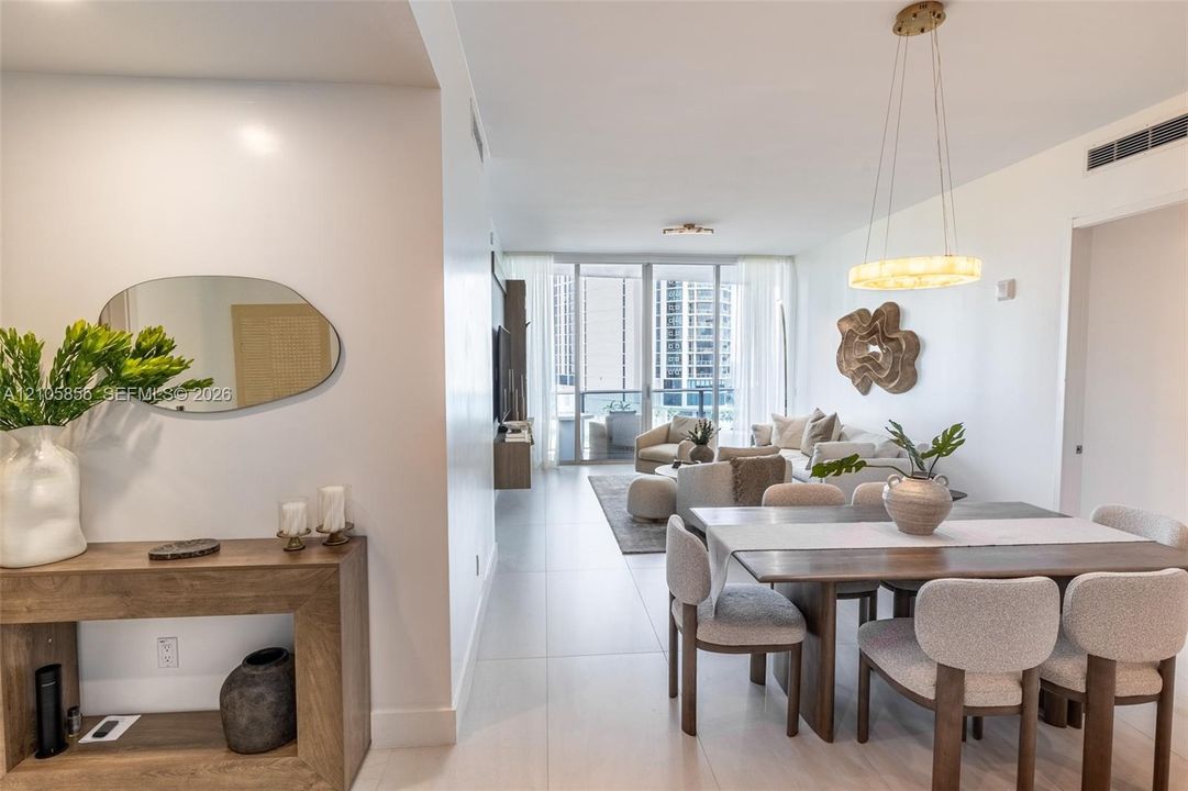 Large-format tile flooring, circular pendant lighting, and floor-to-ceiling glass doors opening to a balcony