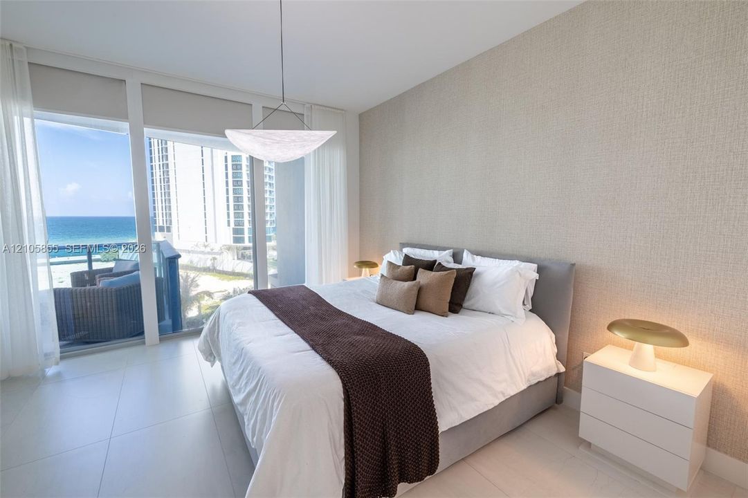 Floor-to-ceiling windows, textured wall covering, large-format tile flooring, modern bowl pendant lighting, and private balcony