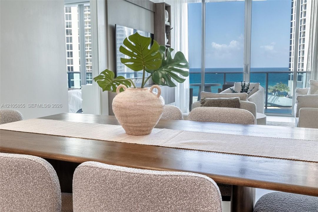 Floor-to-ceiling glass wall, private balcony with metal railing, and ocean horizon backdrop