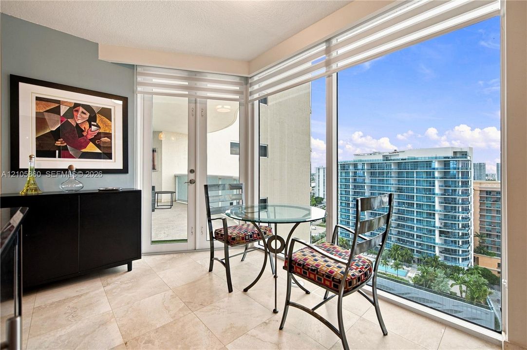 Floor-to-ceiling windows, large-format tile flooring, and glass-paneled double doors providing outdoor access to a private balcony