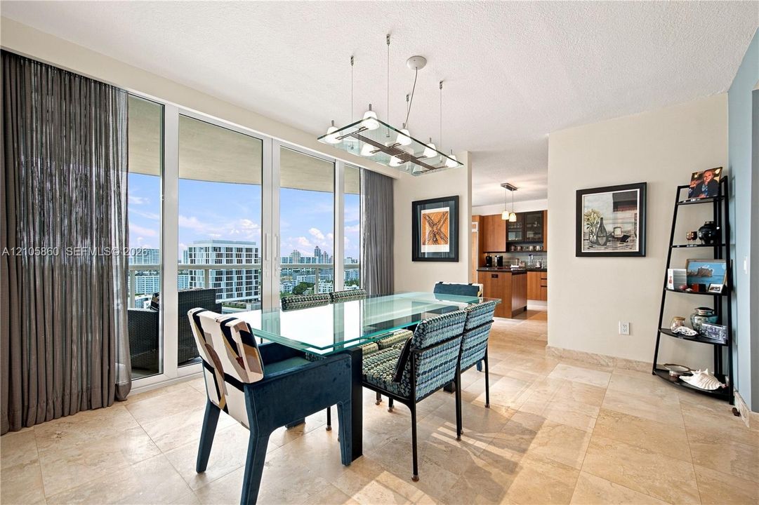 Floor-to-ceiling glass panel windows, light-toned stone tile flooring, and a multi-light contemporary pendant fixture