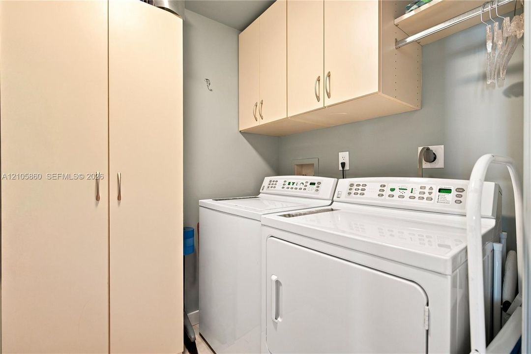 Laundry area featuring full-height pantry-style cabinetry, overhead wall-mounted storage cabinets, and a horizontal hanging rod
