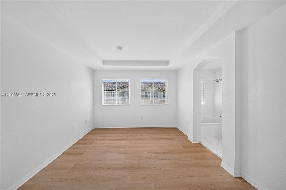 Interior space featuring wood-finish flooring, a recessed tray ceiling, and dual windows