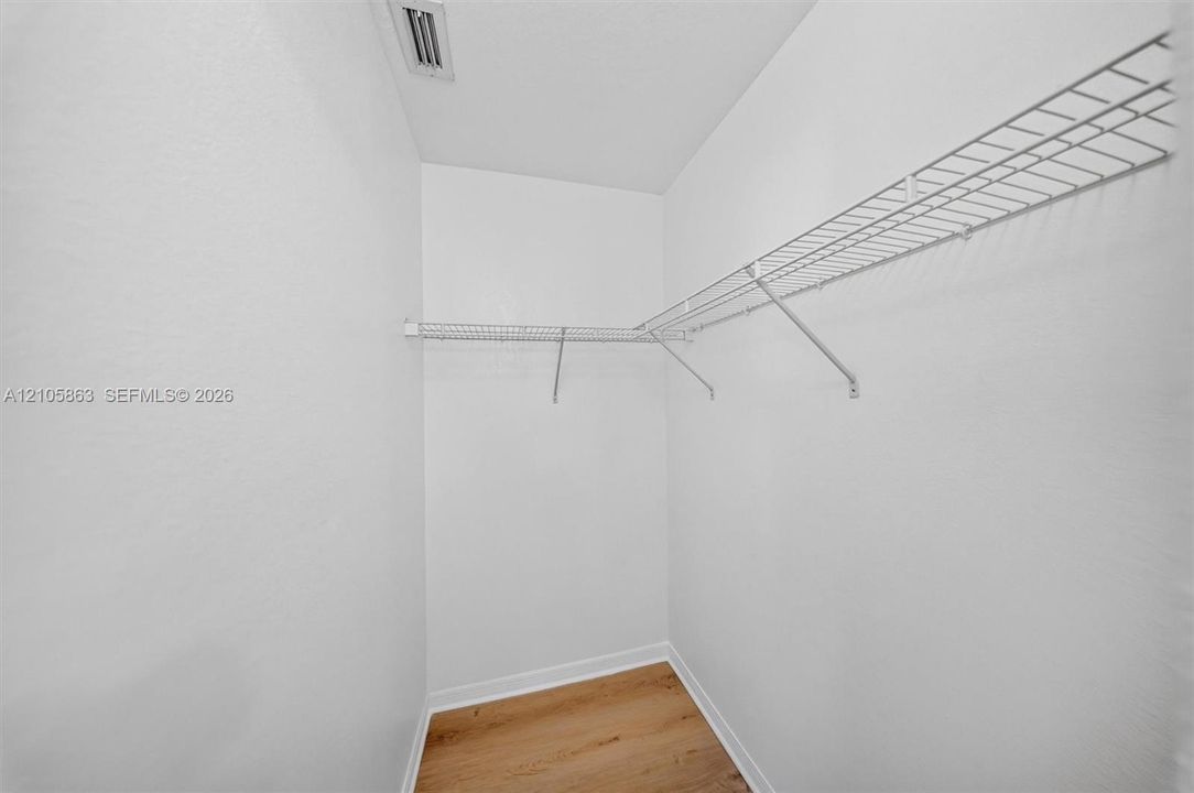 Storage area featuring wood-finish flooring and L-shaped wire shelving