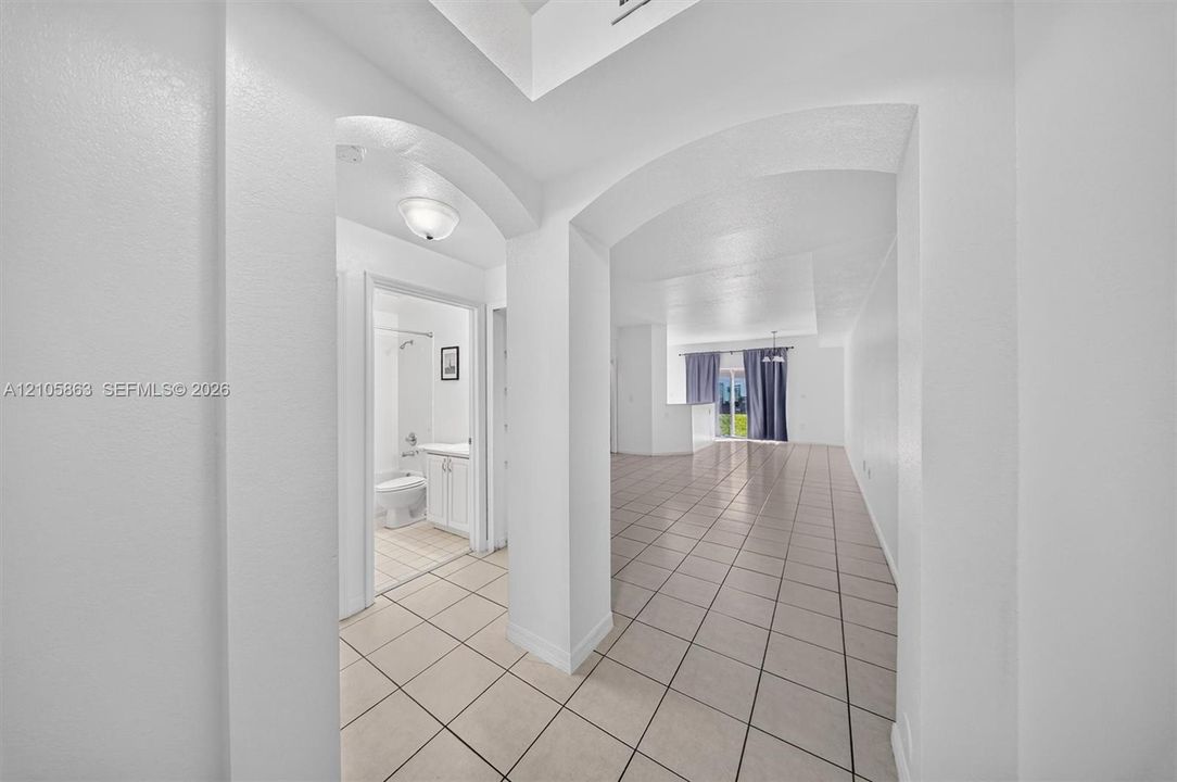 Interior featuring ceramic tile flooring, arched doorways, recessed ceiling detail, and neutral wall tones