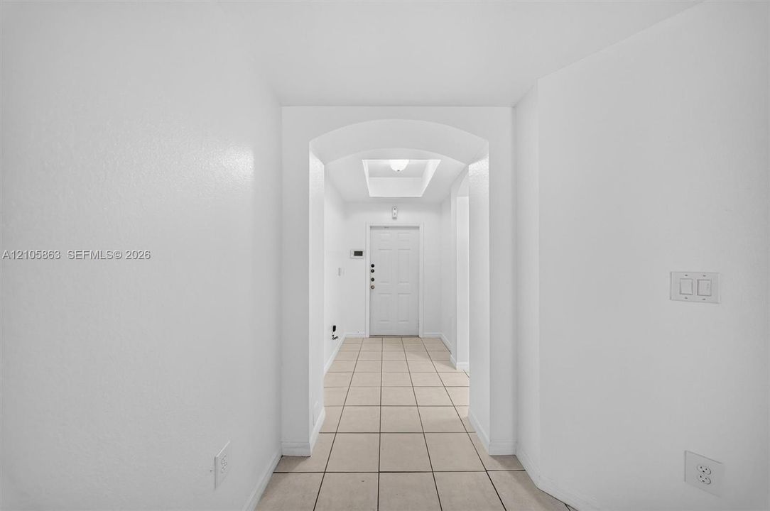 Entryway featuring tile flooring, an arched threshold, a recessed ceiling tray, and a paneled entry door