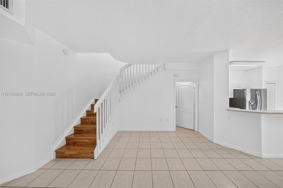 Interior featuring tiled flooring, a staircase with wood-finish treads, and a white balustrade