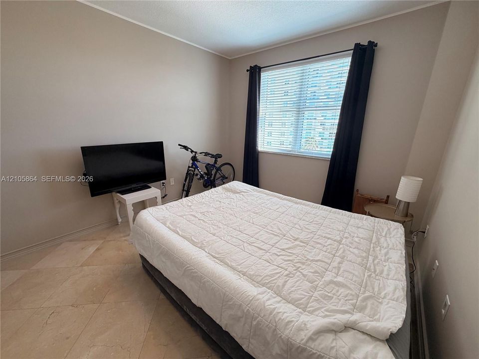 Neutral-toned walls, large window with horizontal blinds, and tile flooring