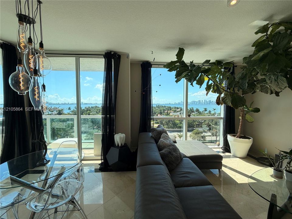 Floor-to-ceiling windows, polished stone flooring, multi-pendant Edison-style lighting, and glass balcony railings