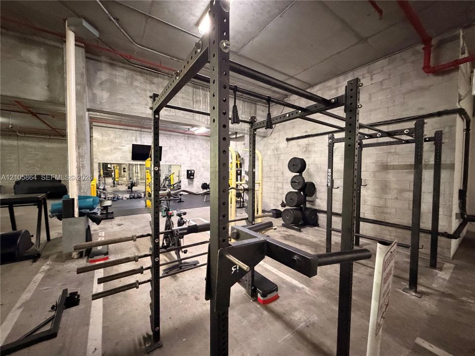 Industrial-style fitness space featuring concrete block walls, exposed structural elements, and concrete flooring