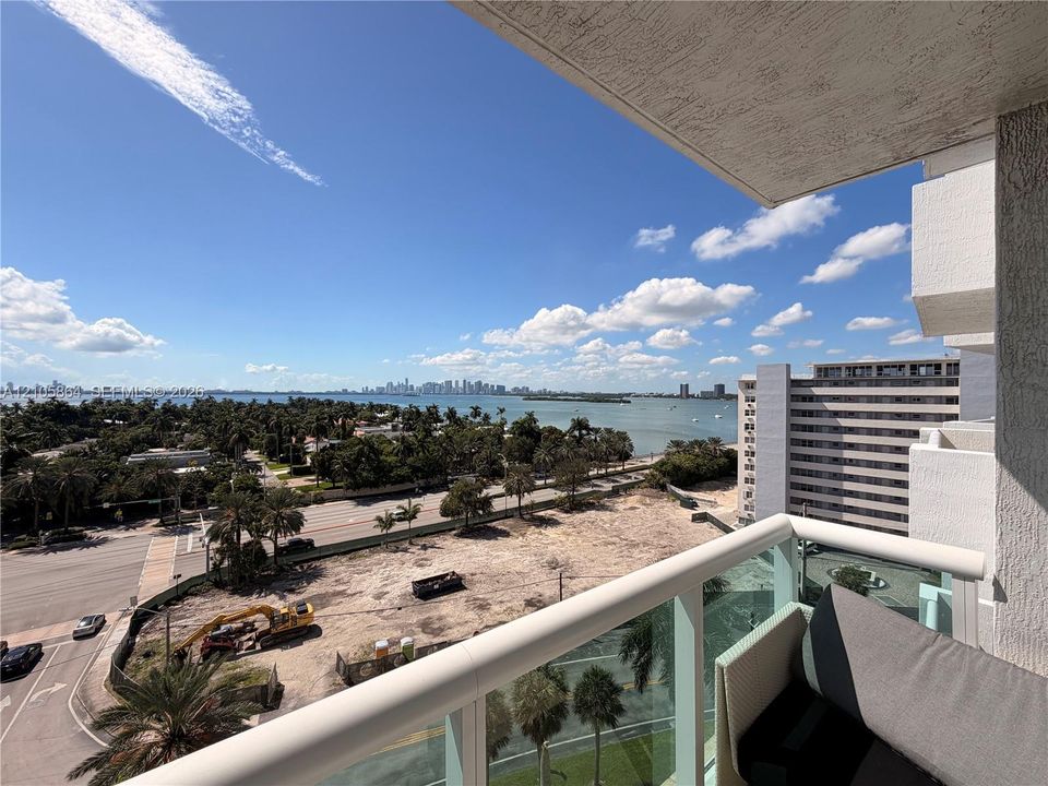 Private balcony with a glass and metal railing, featuring panoramic coastal and city skyline scenery