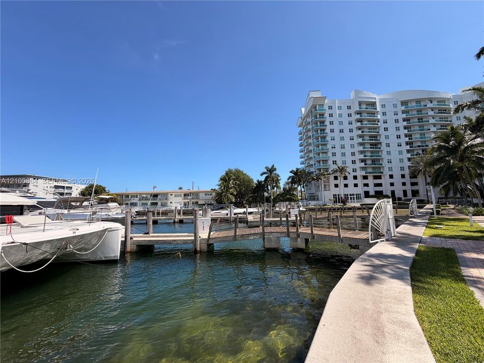 Waterfront property featuring a private boat slip, wooden pier, paved walkway, and landscaping