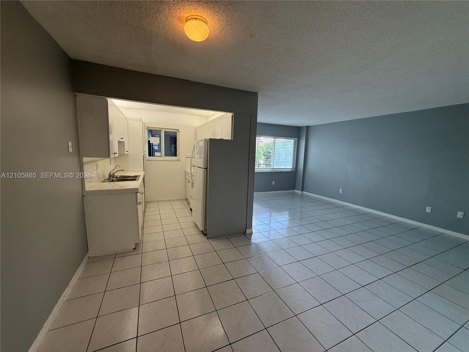 Interior space featuring uniform ceramic tile flooring, kitchen with white cabinetry, dual-basin sink, and natural light via windows