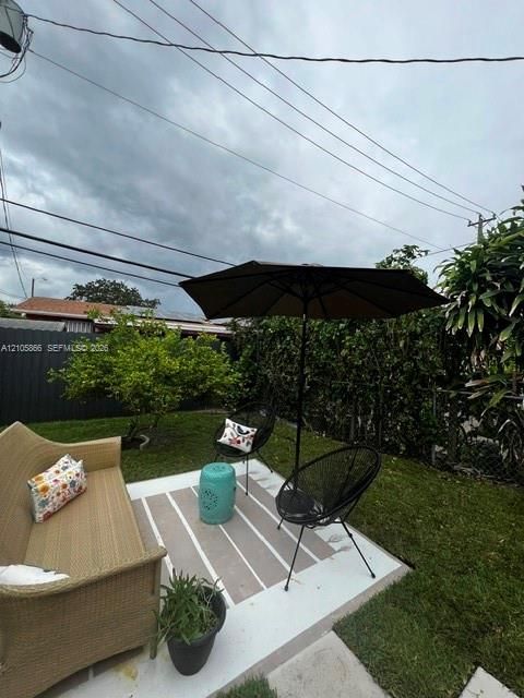 1/1's Backyard featuring a concrete patio, perimeter privacy fencing, and established shrubbery