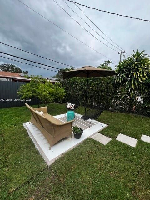 1/1's Backyard featuring a concrete patio, perimeter privacy fencing, and established shrubbery