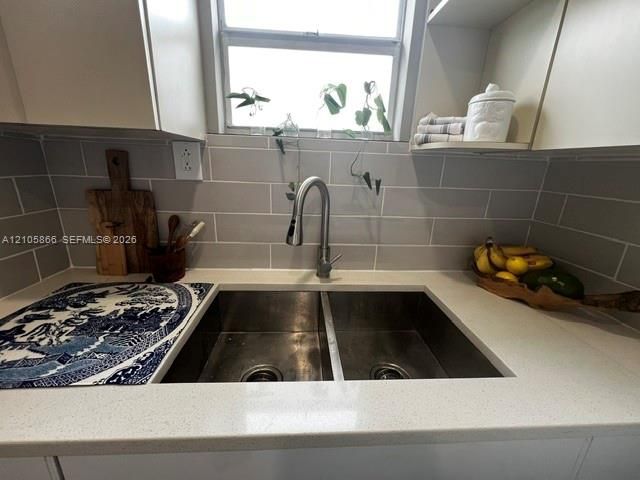 1/1 Kitchen Dual-basin stainless steel undermount sink with a gooseneck pull-down faucet, quartz countertops, and a light-toned subway tile backsplash