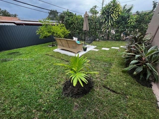 1/1 's Backyard featuring a grass lawn, paved square patio area, perimeter fencing, and established landscape plantings