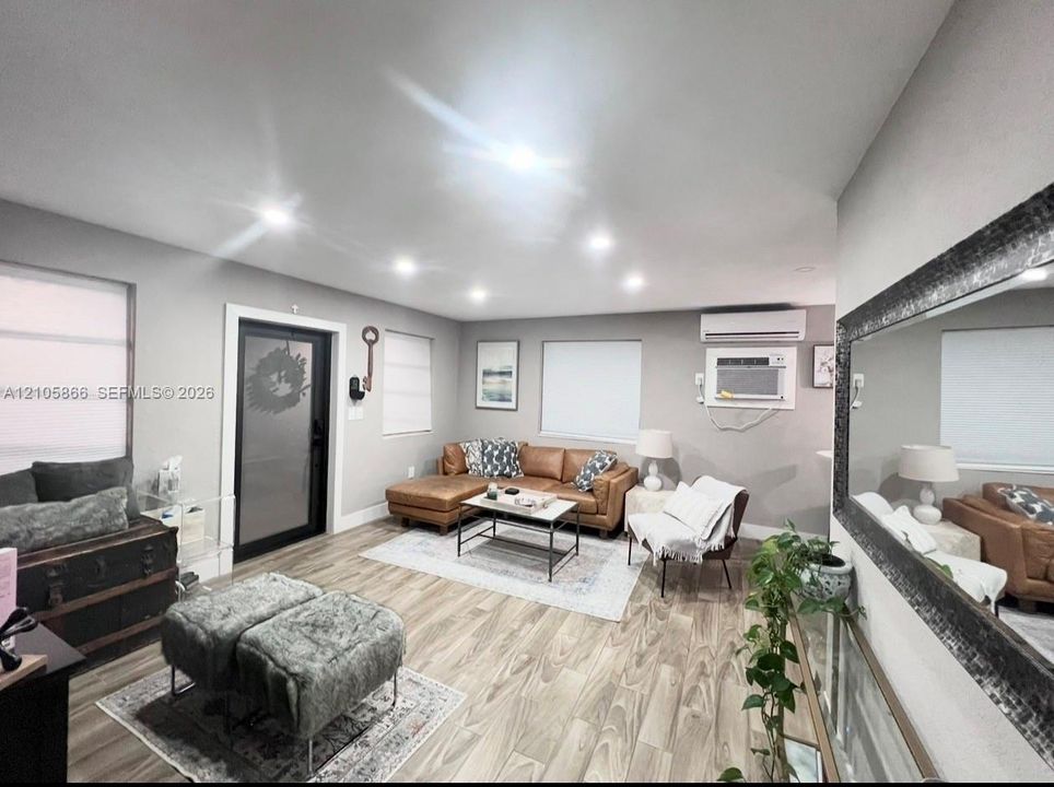 Interior space featuring wood-finish flooring, recessed lighting, wall-mounted air conditioning unit, and a glass-paneled exterior door