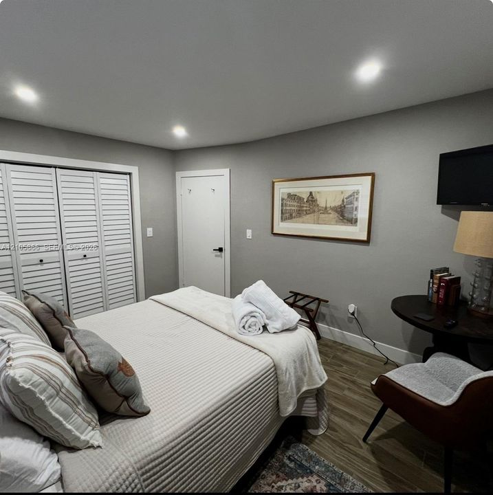 main house bedroom 2 Wood-finish flooring, recessed lighting, and white louvered closet doors