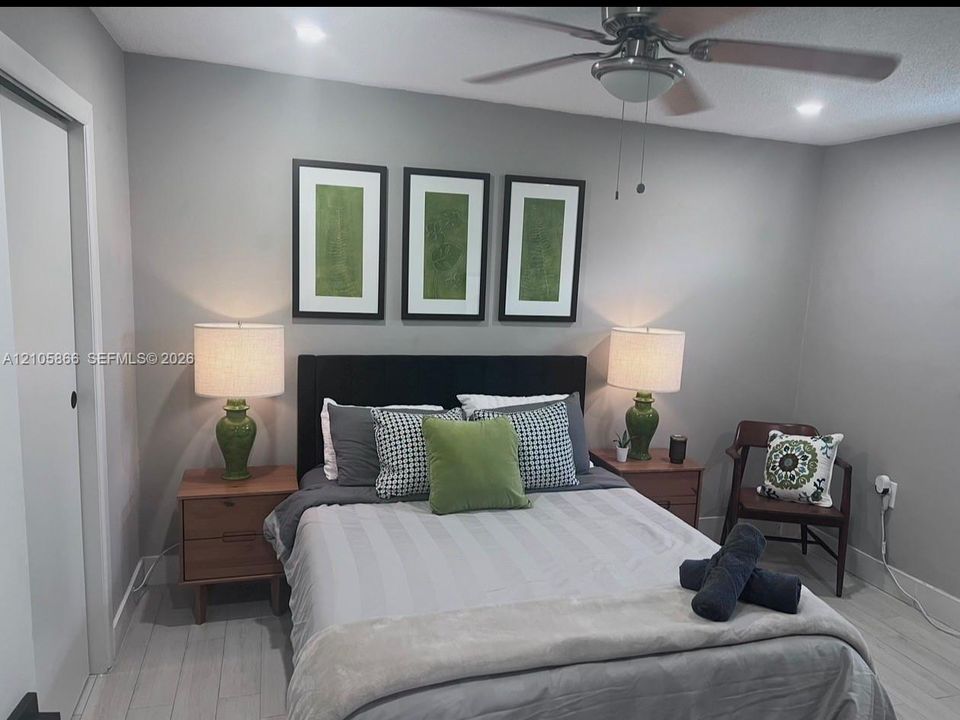 Neutral-toned walls paired with light wood-finish flooring and a ceiling-mounted light fixture with an integrated fan