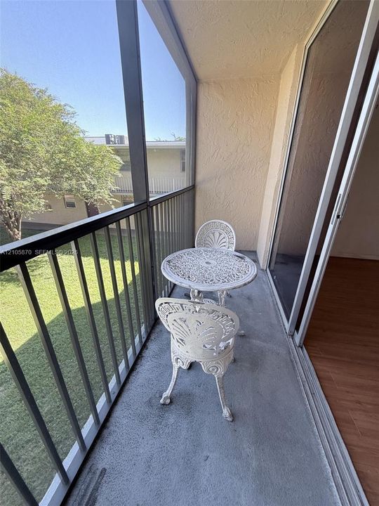 Screened-in balcony featuring concrete flooring, a metal frame enclosure, and sliding glass door access