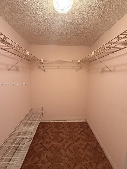 Walk-in closet featuring tiered wire shelving and patterned vinyl flooring
