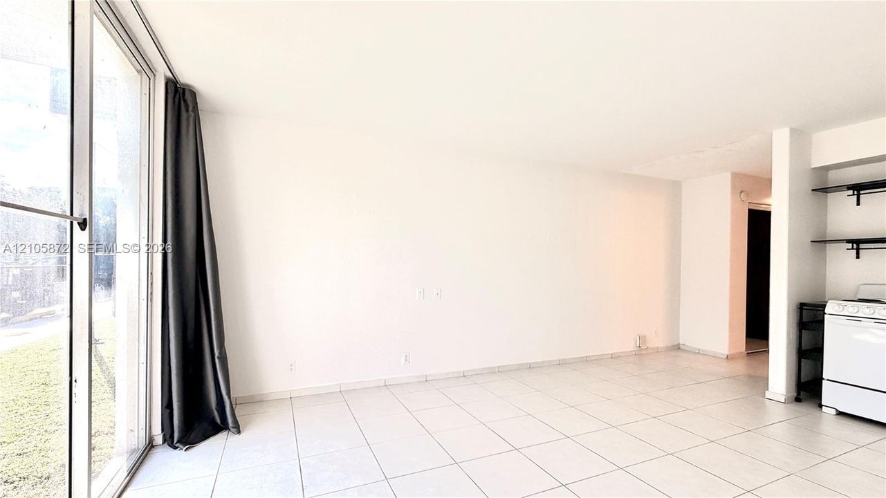 Open living area featuring large sliding glass doors, neutral tile flooring, and built-in wall shelving
