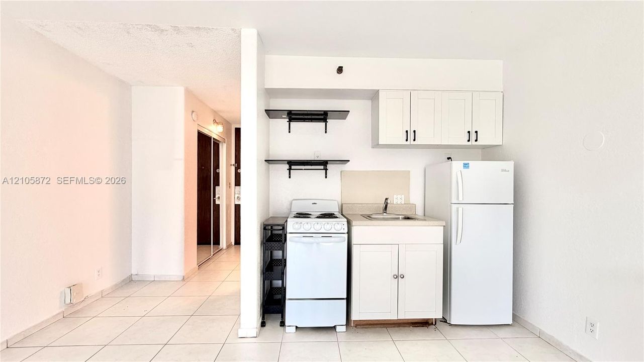 Kitchenette featuring white cabinetry, open shelving, tile flooring, and integrated white appliances