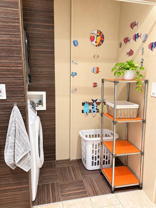 Laundry space featuring horizontal wood-finish wall paneling, large-format neutral wall tile, and recessed laundry hookups