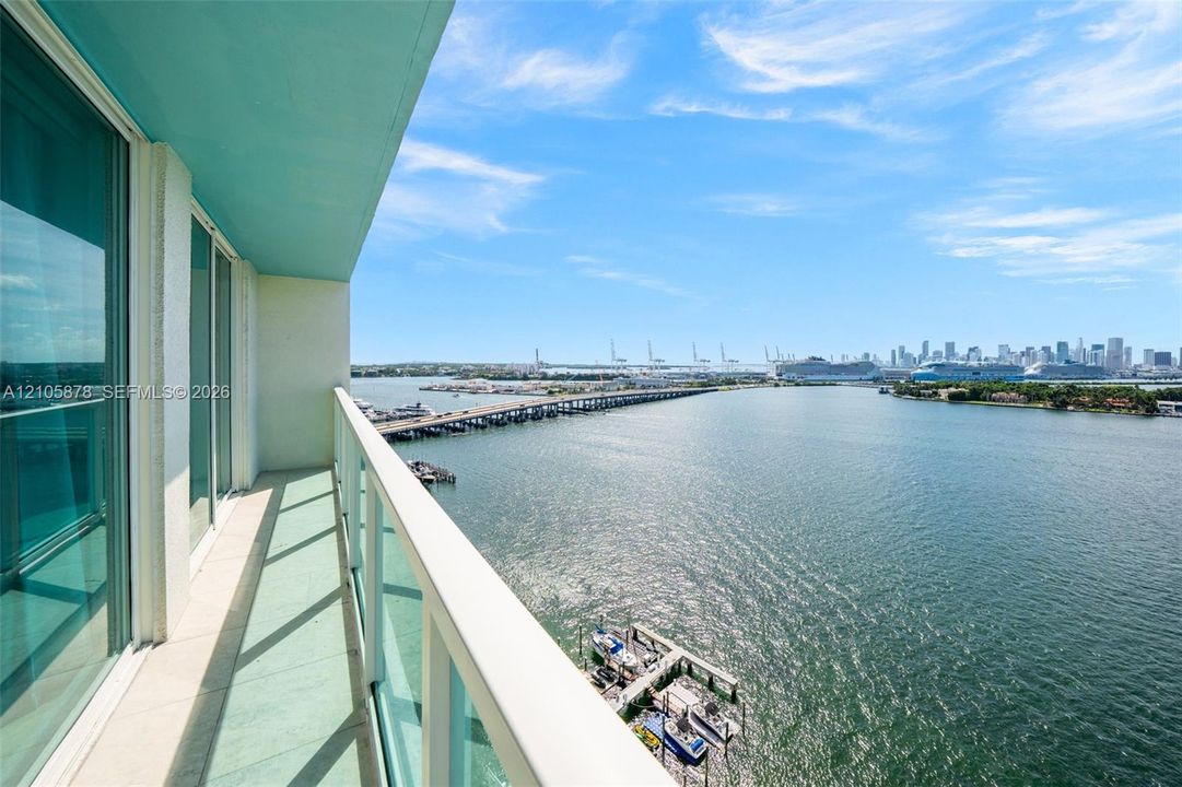 Waterfront balcony with floor-to-ceiling glass doors, expansive bay vistas, and modern glass railings