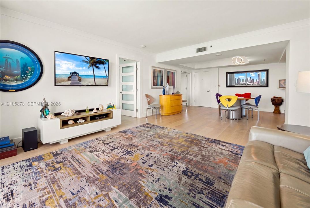 Open-concept interior featuring light wood-finish flooring, recessed lighting, and a multi-panel door with frosted glass inserts