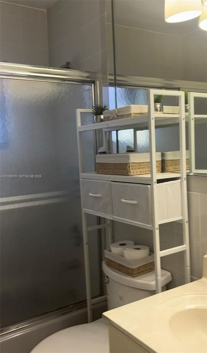 Bathroom featuring a shower stall with a framed sliding glass enclosure, a vanity with an integrated basin, and a wall-mounted mirror