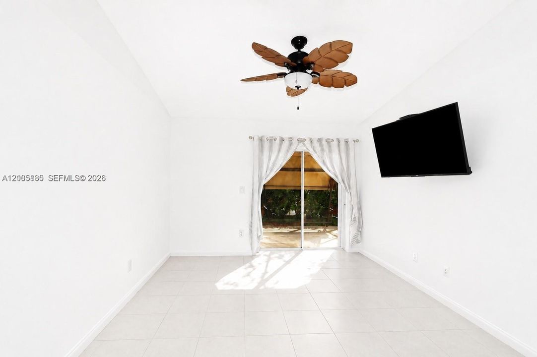 Light-filled room featuring large-format tile flooring, a palm-leaf style ceiling fan, and sliding glass doors