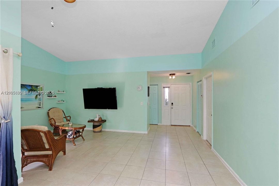 Vaulted ceilings, neutral tile flooring, and a multi-panel front door with sidelight window