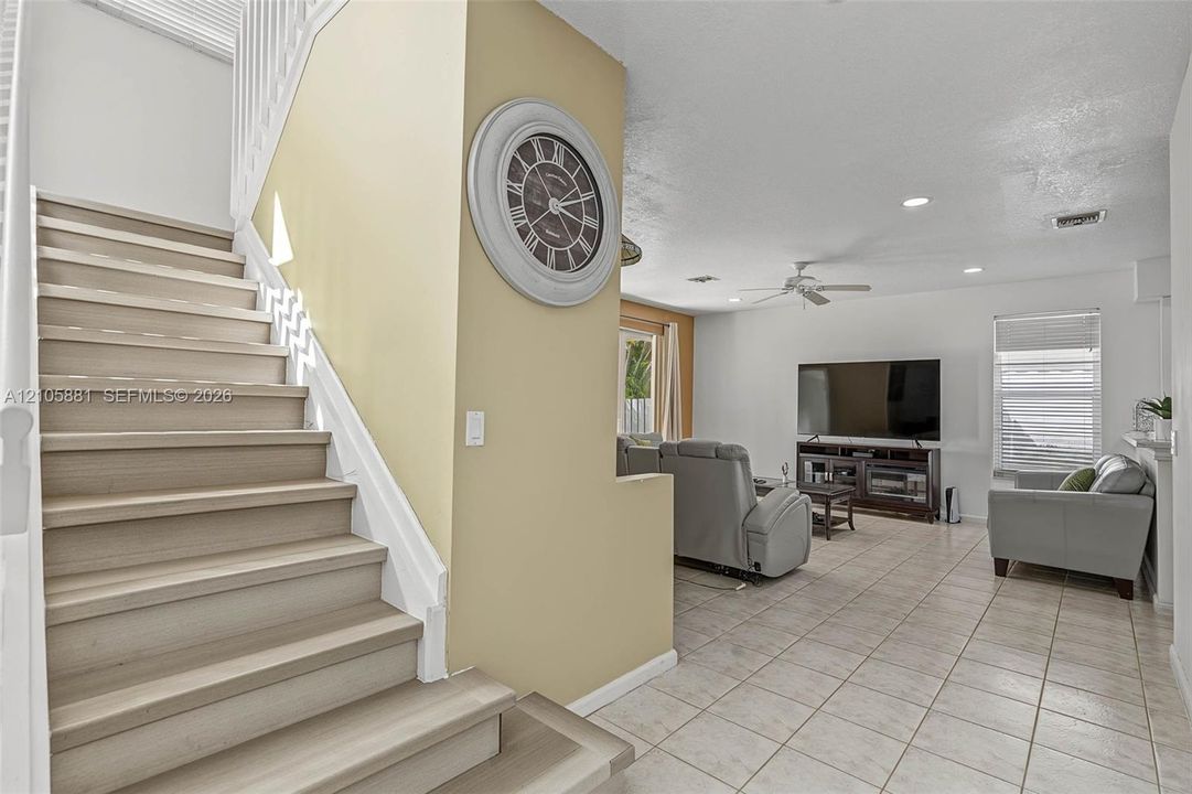 Staircase with wood-finish treads and white railing, tile flooring, recessed lighting, and ceiling fan