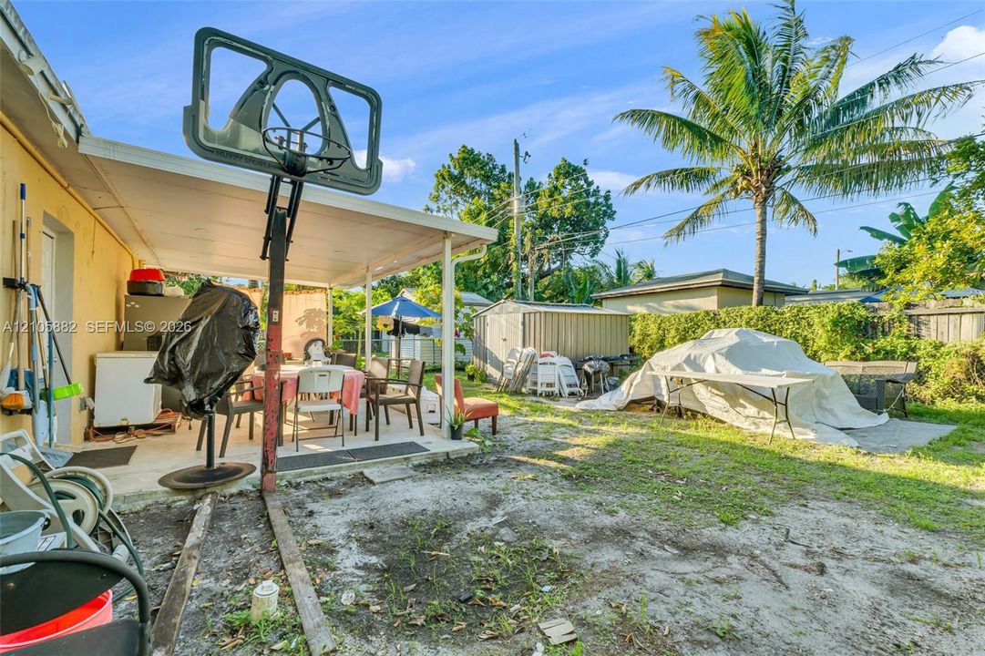 Covered concrete patio with support columns and backyard storage shed